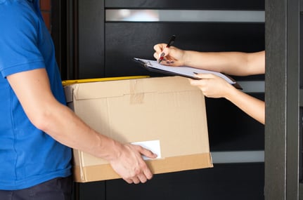 Delivery guy holding package while woman is signing documents