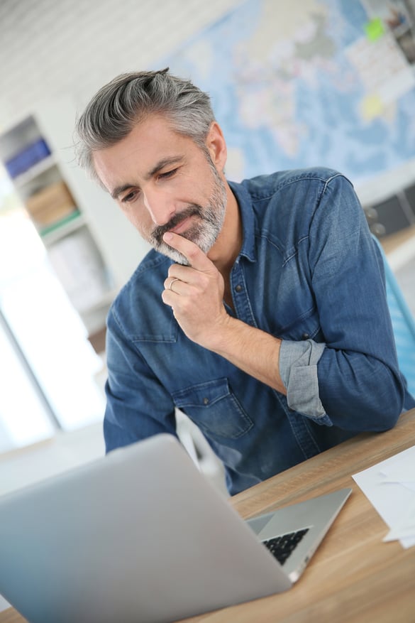 Mature man working on laptop in school office