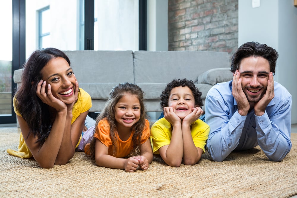 Smiling family on carpet in living room posing for the camera