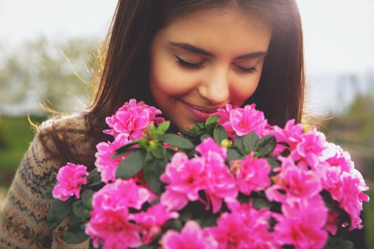 Young cute woman smelling pink flowers